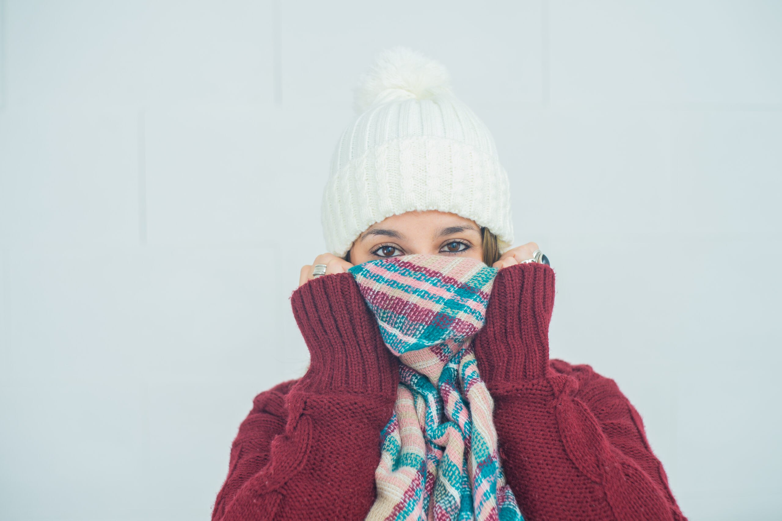 A closeup shot of a girl with her face wrapped up in a scarf on white background